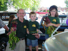 Market manager Ray Satterfield and Grand children display fresh produce for sale.